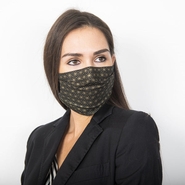 Female model wearing a black fabric face mask with a metallic golden Japanese geometric star print.